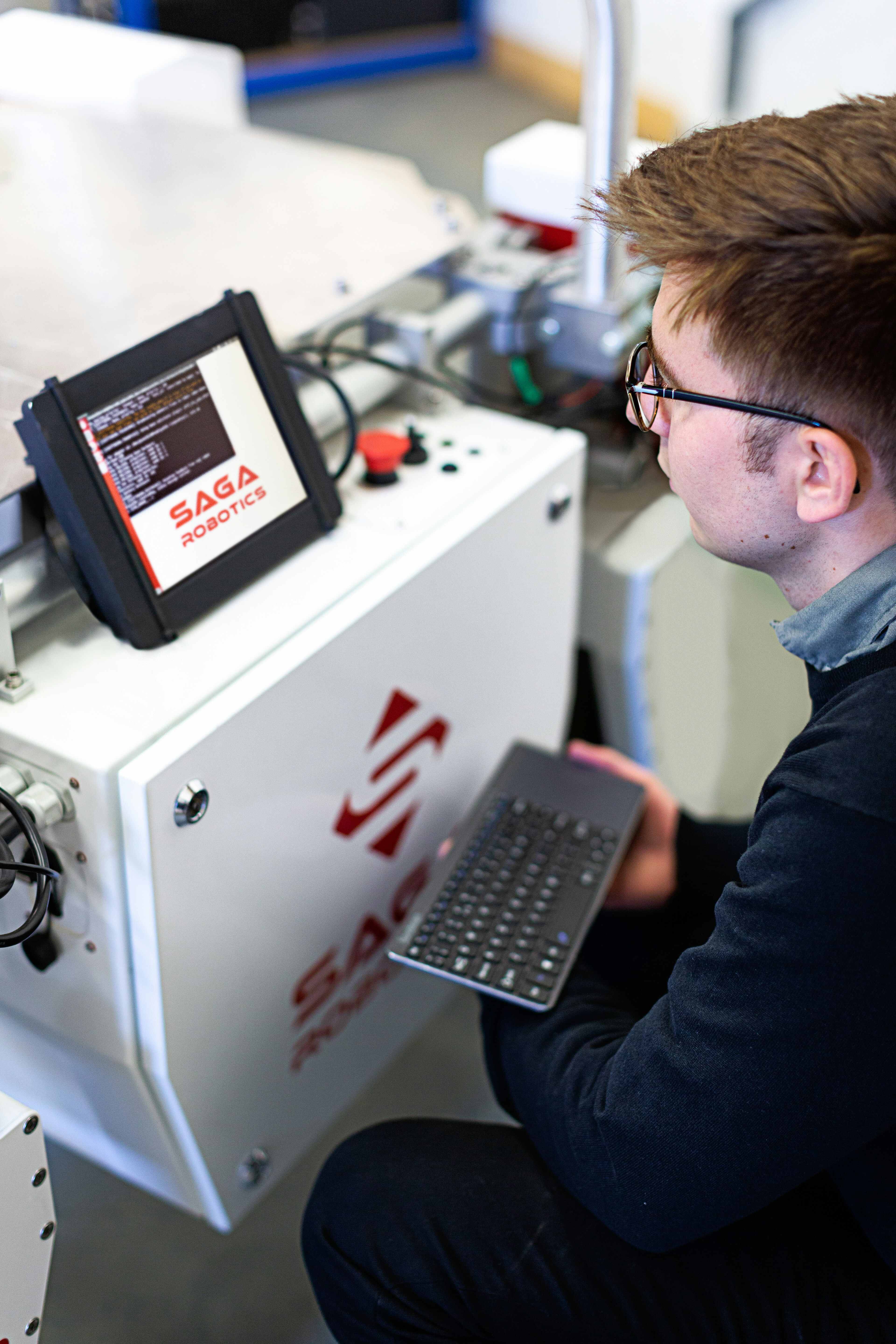 A technician programming a Saga Robotics control unit using a wireless keyboard and integrated display.